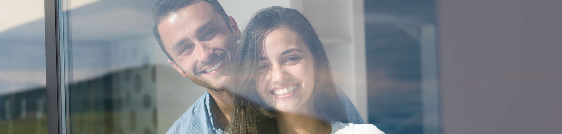 Two people looking out of their apartment window that has fully internal air conditioning without an outside unit for apartments installed by Cool You